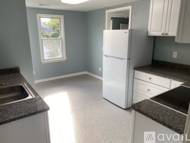 A kitchen with a white refrigerator, sink, and cabinets.