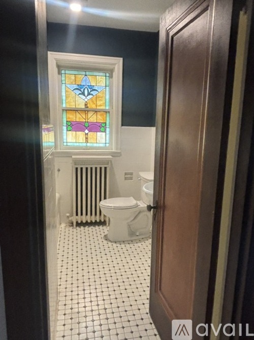A bathroom with a toilet, sink and a stained glass window.