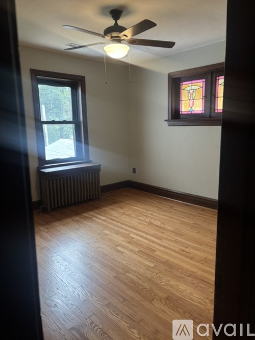 A room with a ceiling fan and a window with a radiator under it.