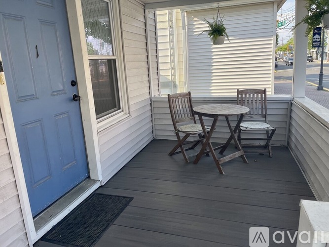A small table and two chairs are on a porch.