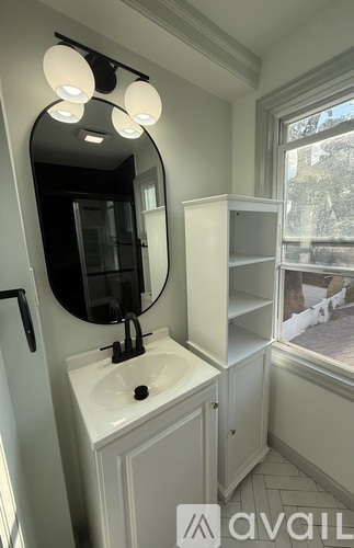 A bathroom with a sink, mirror, and cabinet.