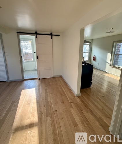 A room with wooden flooring and a sliding door leading to a balcony.