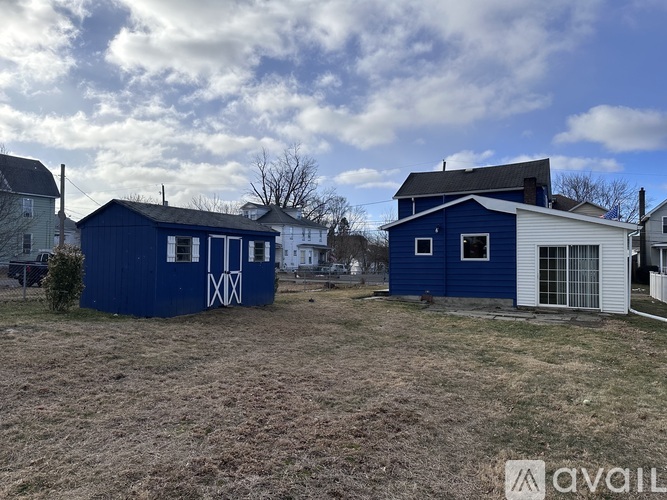 Two blue houses with white trim are situated in a grassy field.