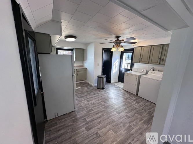 A kitchen with a refrigerator, cabinets, and a ceiling fan.