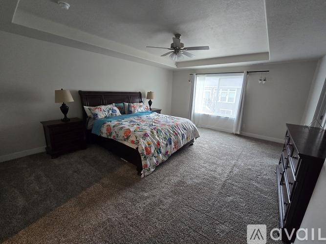 A bedroom with a bed, two lamps, and a ceiling fan.