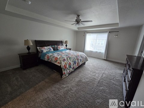 A bedroom with a bed, two lamps, and a ceiling fan.