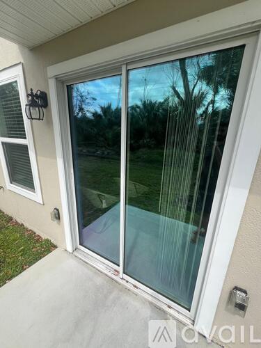 A sliding glass door with a view of trees and a lawn.