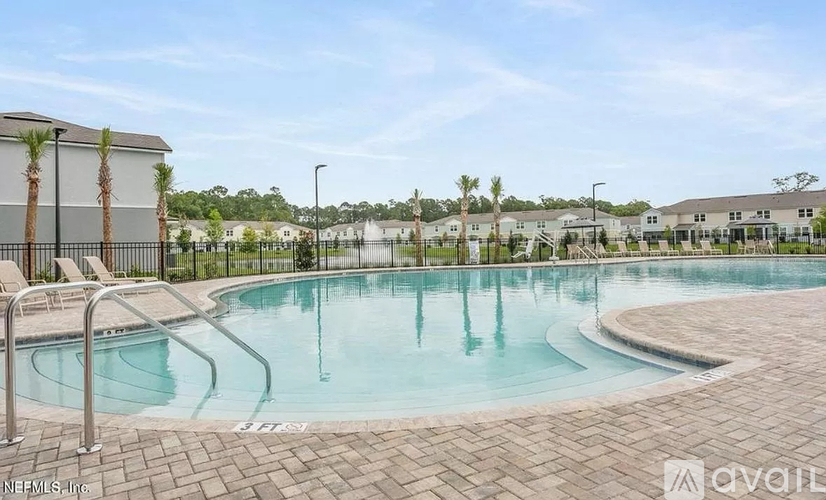 A swimming pool surrounded by a brick patio and palm trees.