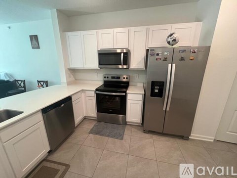 A kitchen with white cabinets and a stainless steel refrigerator.