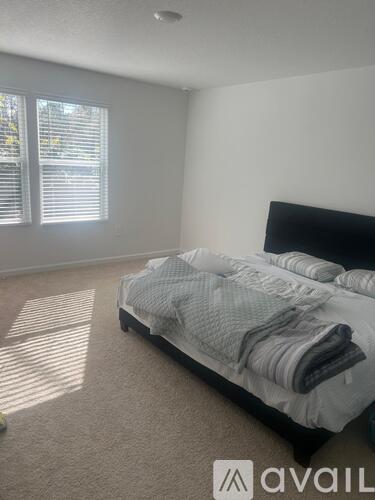 A bedroom with a bed and a window with blinds.