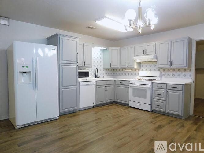 A kitchen with white cabinets and a wooden floor.