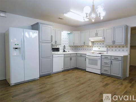 A kitchen with white cabinets and a wooden floor.
