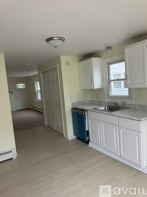 A kitchen with white cabinets and a blue trash can.