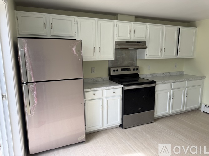 A kitchen with a stainless steel refrigerator and white cabinets.