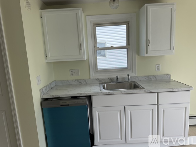 A kitchen with a blue fridge and white cabinets.