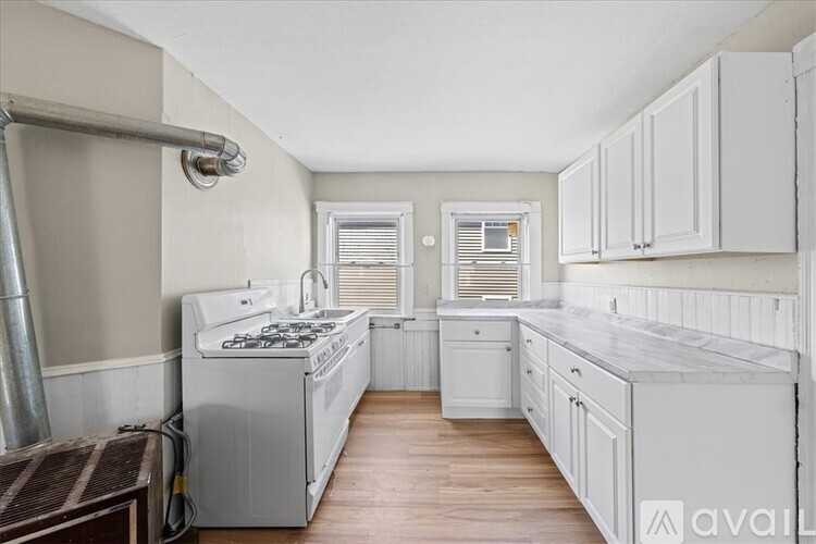 A kitchen with white cabinets and a marble countertop.