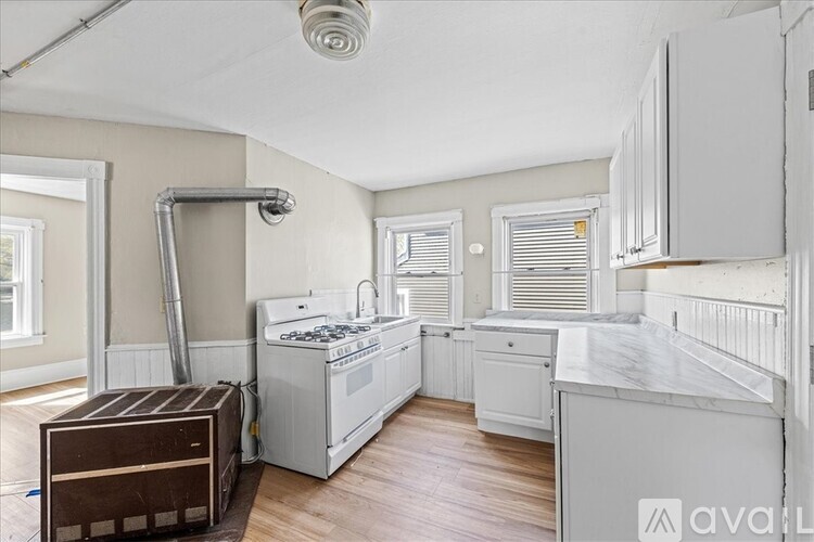 A kitchen with white cabinets and a wooden floor.