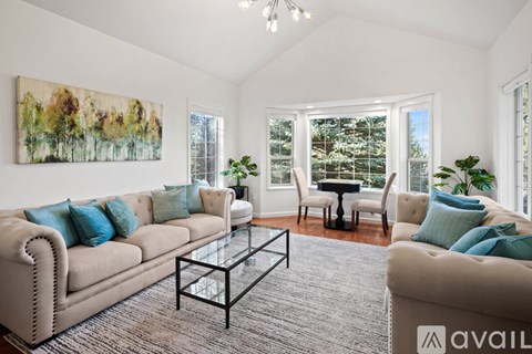 A living room with a large beige sofa, a glass coffee table, and a painting on the wall.