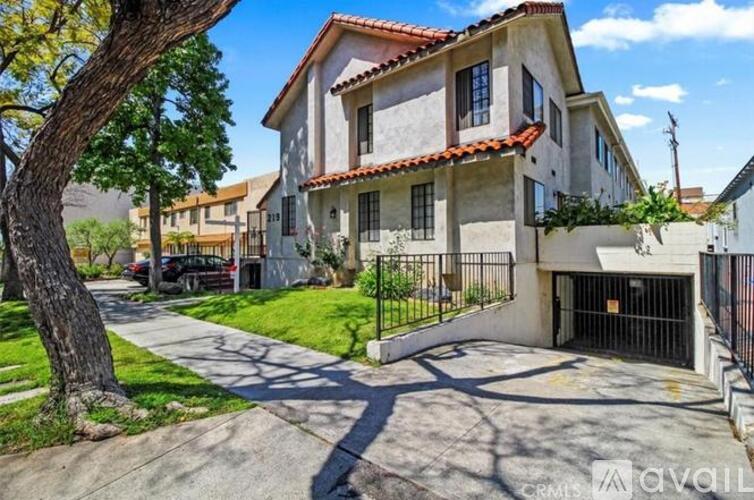 A house with a driveway and a tree in front of it.