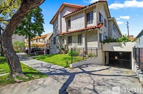 A house with a driveway and a tree in front of it.