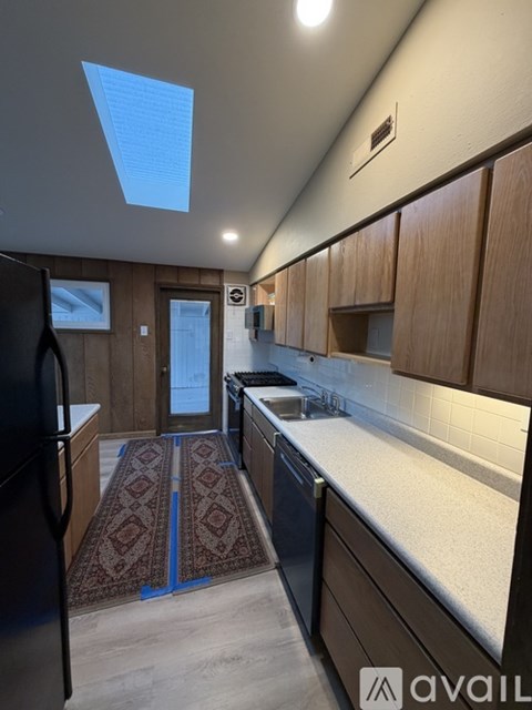 A kitchen with wooden cabinets and a black refrigerator.