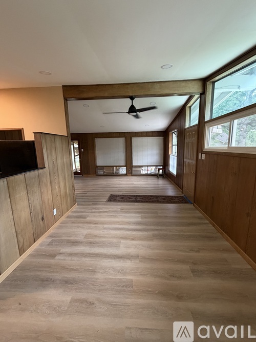 A spacious room with wooden floors and a ceiling fan.