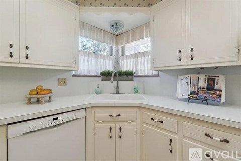 A kitchen with white cabinets and a white dishwasher.