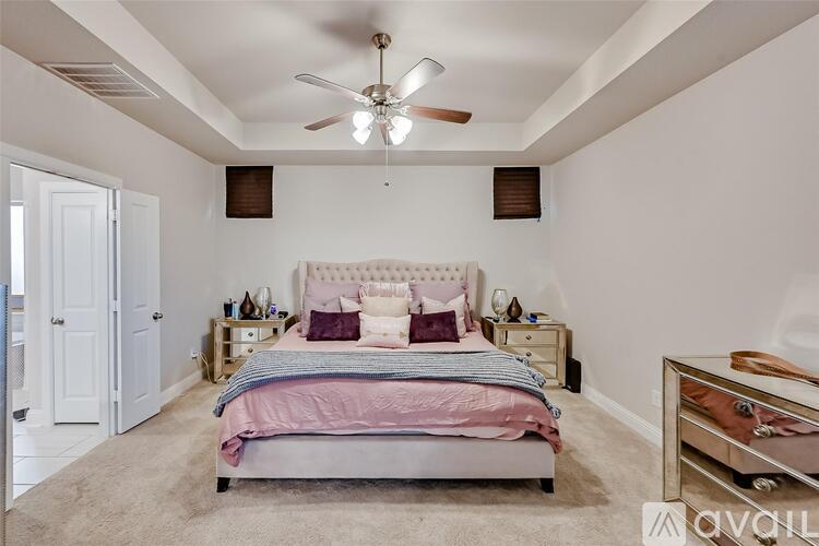 A bedroom with a bed, nightstands, and a ceiling fan.