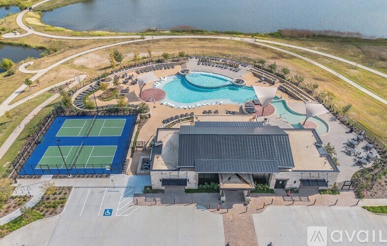 An aerial view of a tennis court, a swimming pool, and a building with a tennis court roof.