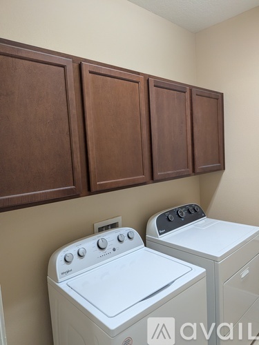 A white washing machine and dryer in front of brown cabinets.