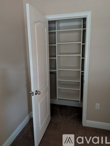 A white door with a glass panel is open to a carpeted hallway.