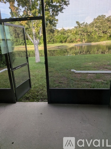 A glass door with a view of a grassy area and a pond.