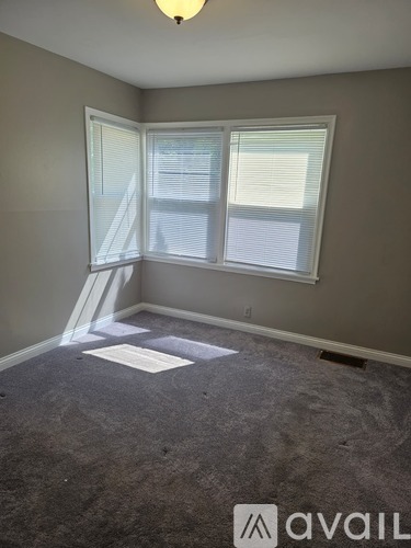 A room with a carpeted floor and a window with blinds.