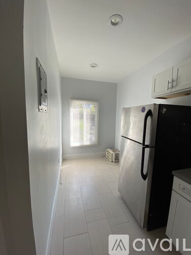 A kitchen with a black fridge and white cabinets.