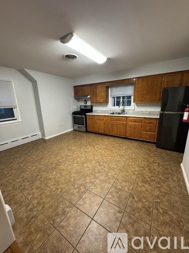 A kitchen with brown tile flooring and wooden cabinets.