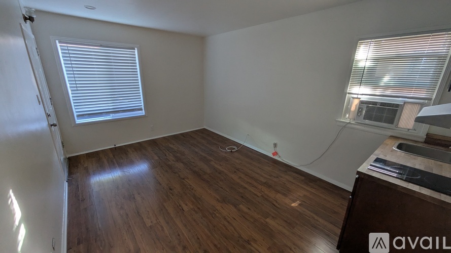 A room with wooden flooring and a window with blinds.