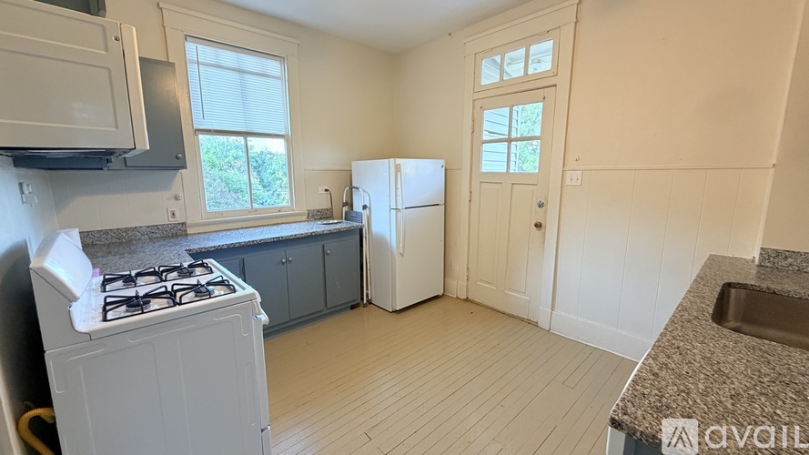 A kitchen with a white stove, a white fridge, and a window.