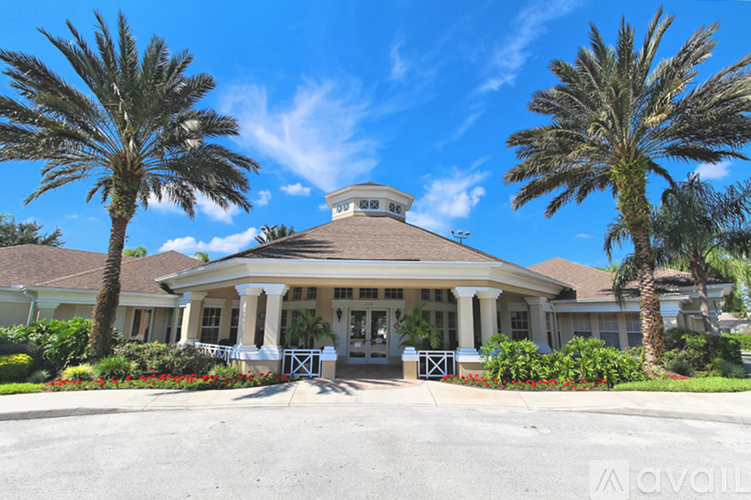 A large house with a gazebo-like structure on the roof is surrounded by palm trees.