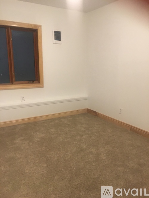 A room with a window and a wall-mounted thermostat.