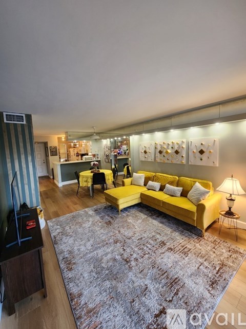 A living room with a yellow couch and a grey rug.