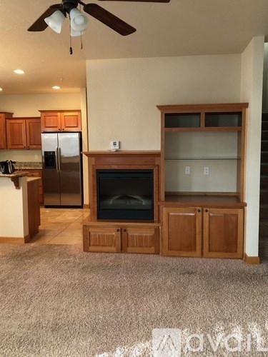 A living room with a fireplace and a refrigerator.
