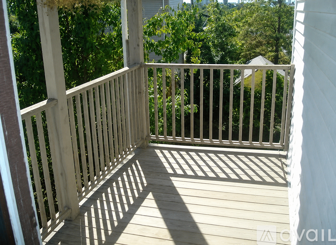 A wooden deck with a white railing and trees in the background.
