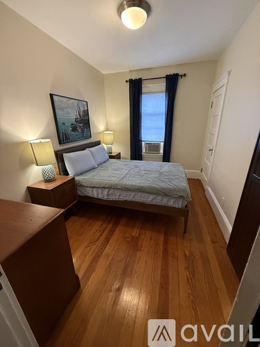 A bedroom with a bed, nightstands, and a painting on the wall.