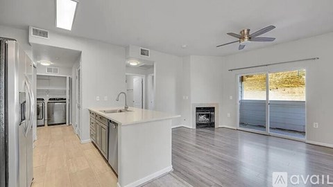 A spacious kitchen with a refrigerator, sink, and a fireplace in the living room.