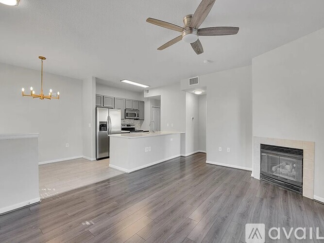 A spacious living room with a fireplace and a ceiling fan.