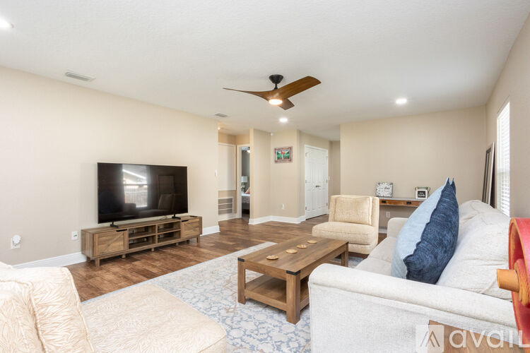 A living room with a flat screen TV and a ceiling fan.