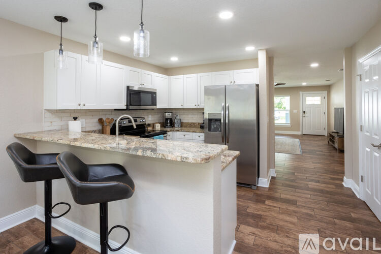 A kitchen with a marble countertop and bar stools.