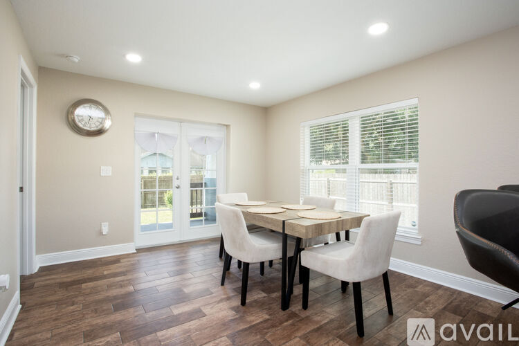 A dining room with a table set for two and a view of a balcony through the window.