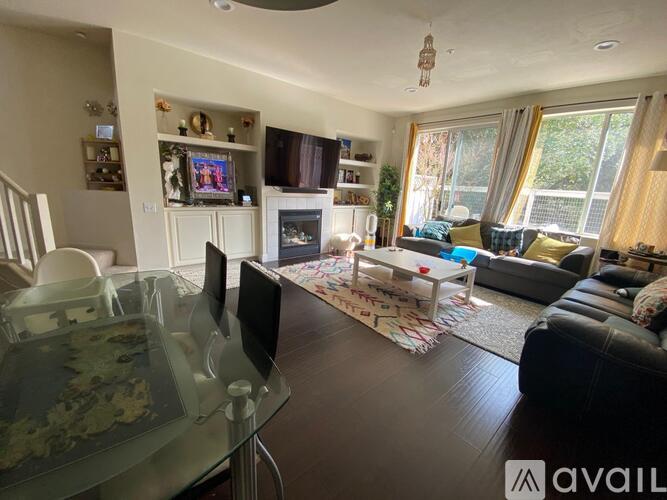 A living room with a glass table and a television on the wall.