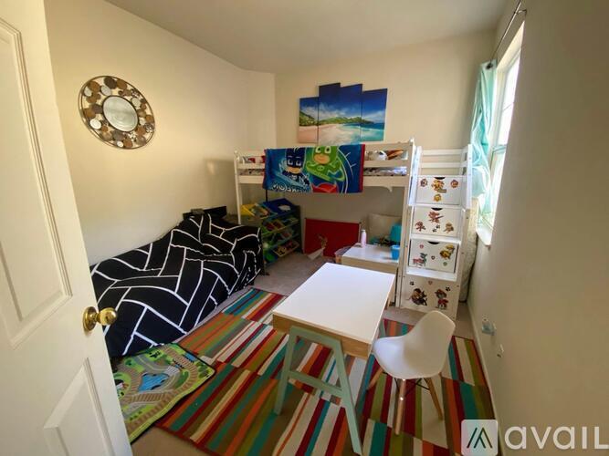 A room with a white desk, a white chair, a bunk bed, and a colorful rug.